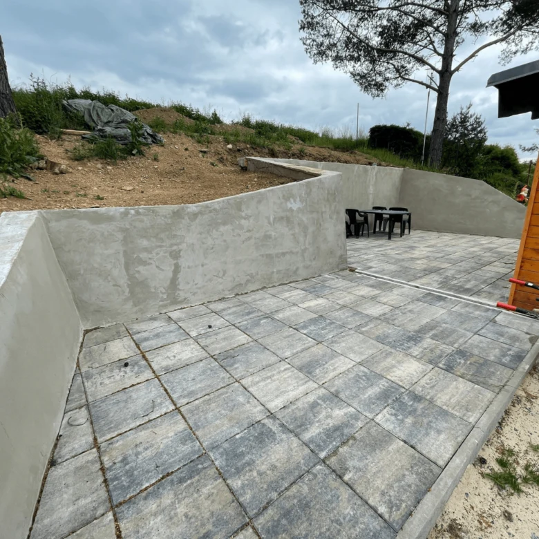 Nová betonová terasa s kamennou dlažbou a zdi.