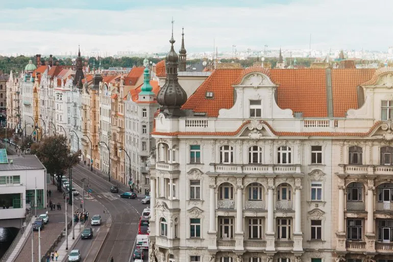 Historické domy s barevnými fasádami a červenými střechami v Praze.