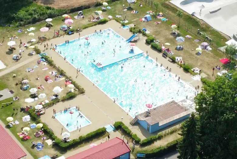 Vzduchem pořízený pohled na venkovní bazén v Sušici s plavci.