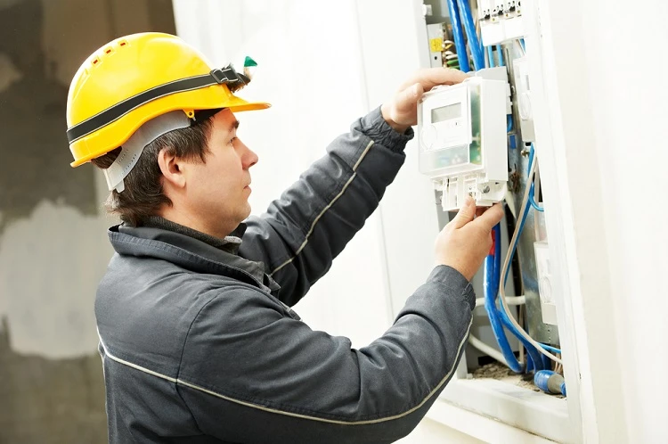 Elektrikář nastavuje elektroměr v rozvaděči s viditelným zapojením kabelů.