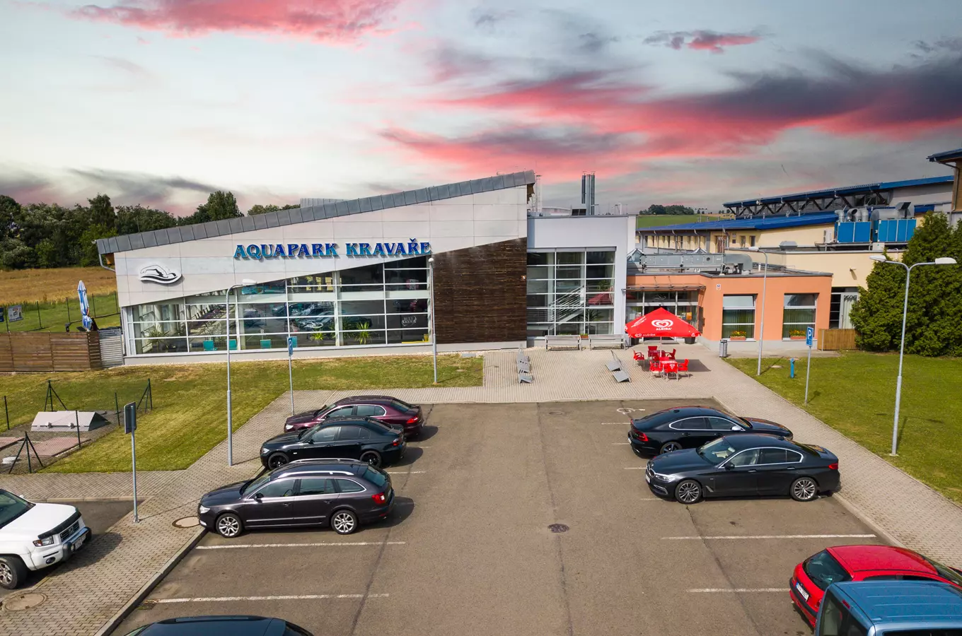 Vnější pohled na Aquapark Kravaře s parkovištěm a vstupní halou.
