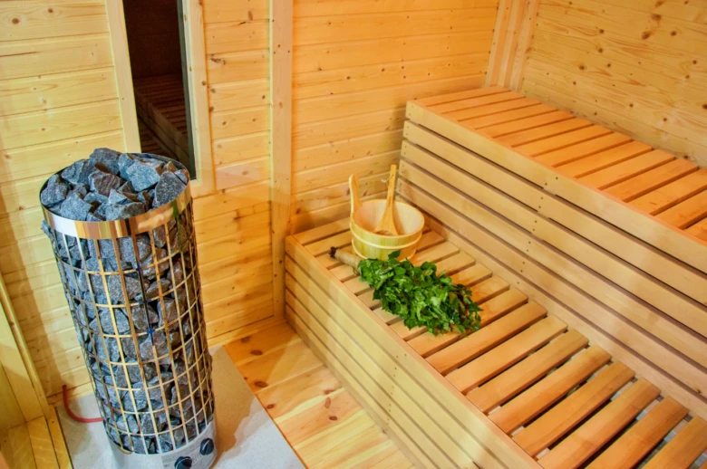 Ukončená finská sauna s elektrickým topidlem a dřevěnými lavicemi.