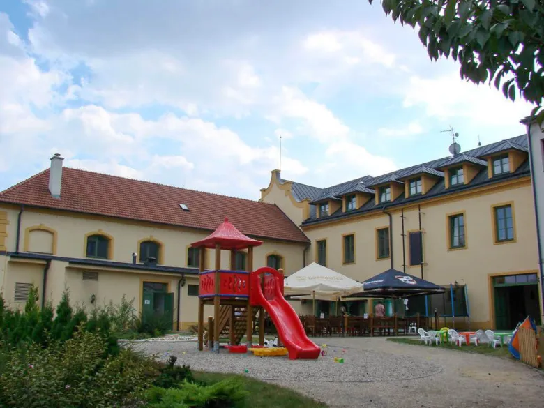 Hřiště s skluzavkou před budovami v areálu koupaliště.