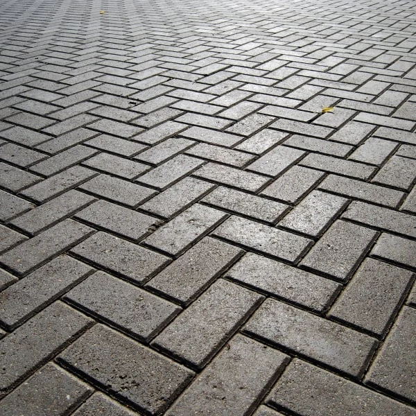 Světle šedá dlažba v ryze správném vzoru 'herringbone' s přesně položenými kameny.