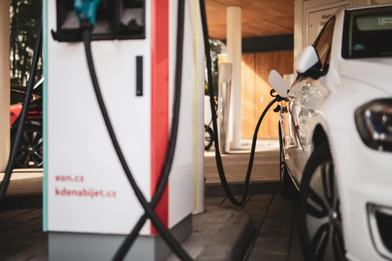 Bílé elektromobil nabíjený na veřejné čerpací stanici.