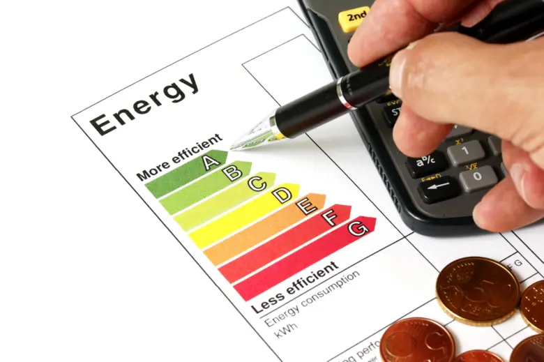 Ruka s tužkou ukazuje na tabulku energetické účinnosti vedle kalkulačky.