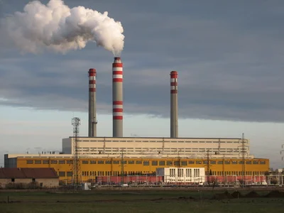 Velká elektrárna na uhlí s třemi vysokými komíny vydávajícími páru.