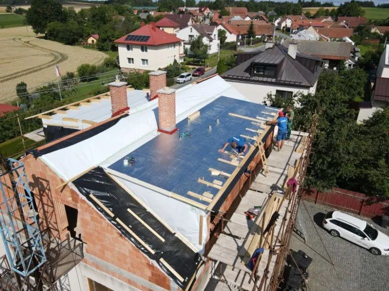 Montáž modrých desek tepelné izolace na střešní konstrukci.
