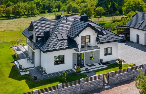 Moderní dům s keramickou střešní krytinou na pozadí zelené krajiny.