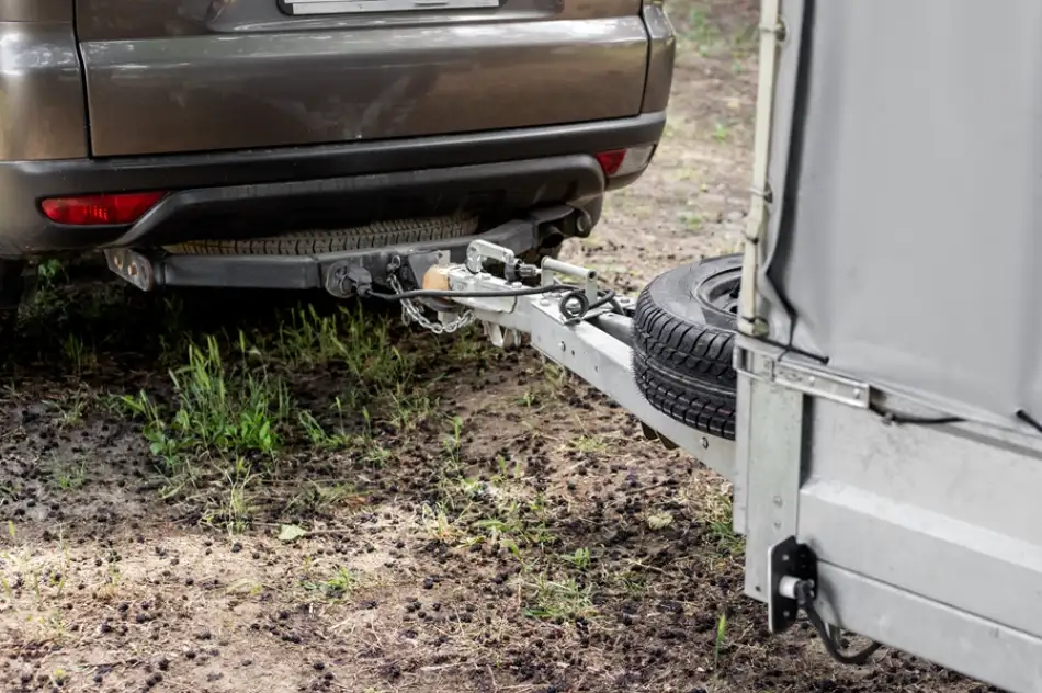 Automobil připojený k malému nákladnímu vozíku na zemi.