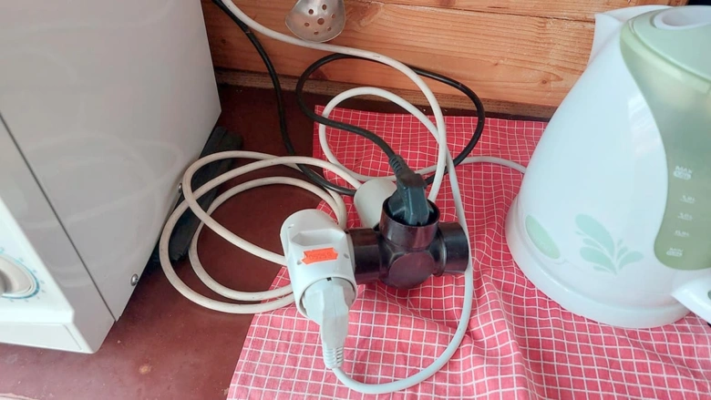 Zamotané elektrické kabely s více zásuvkami na kuchyni