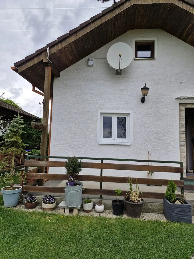 Bílý dům s oknem a rostlinami na schodišti.