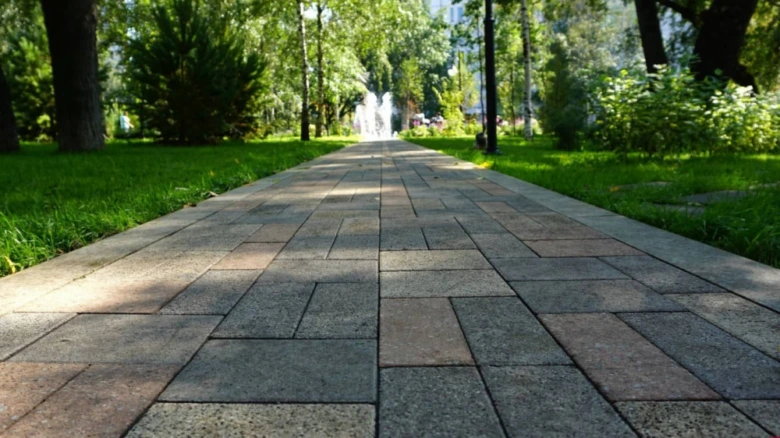Přímá cesta z dlažebních kostek v zeleném parku.