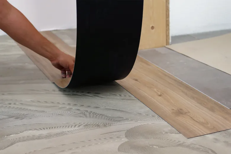 Montáž lepeného vinylového podlahového panelu s odleptovanou zadní stranou.