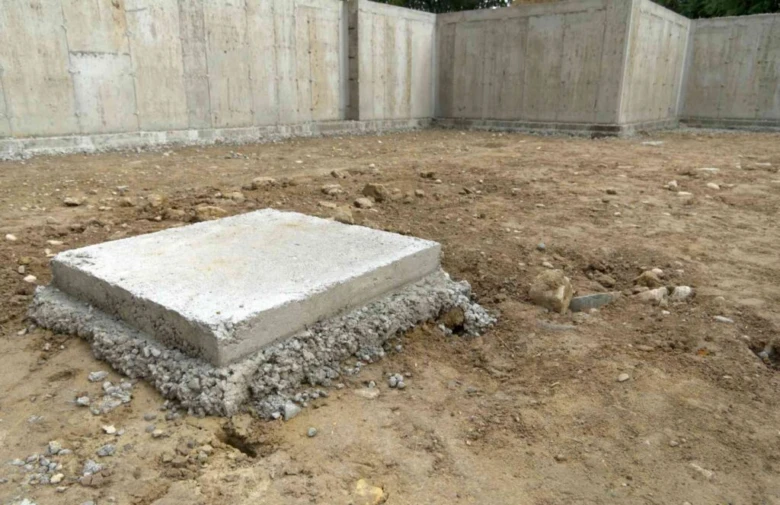 Čerstvě nalitý betonový základní patka pro dřevostavbu na staveništi.