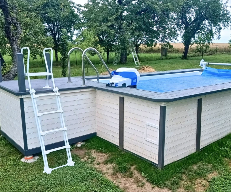 Bílý nadzemní bazén s dřevěným obkladem a schodištěm na trávníku.