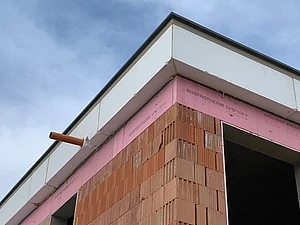 Detailní pohled na stavbu atiky střechy s cihlami a izolací.
