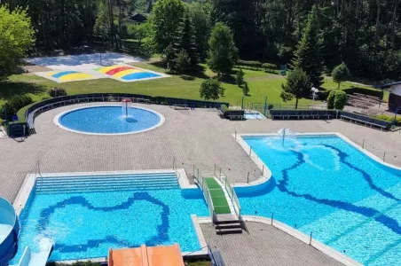 Více bazénů v aquaparku s barevným pozemním uměleckým dílem.
