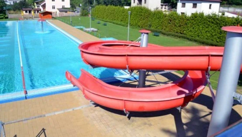 Červená vodní skluzavka vedoucí do bazénu na koupališti