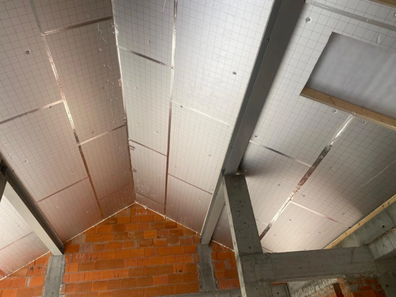 Bílá deska tepelné izolace z materiálu PIR na stropě.