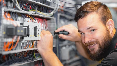Elektrikář montuje komponenty do elektrického rozvaděče.