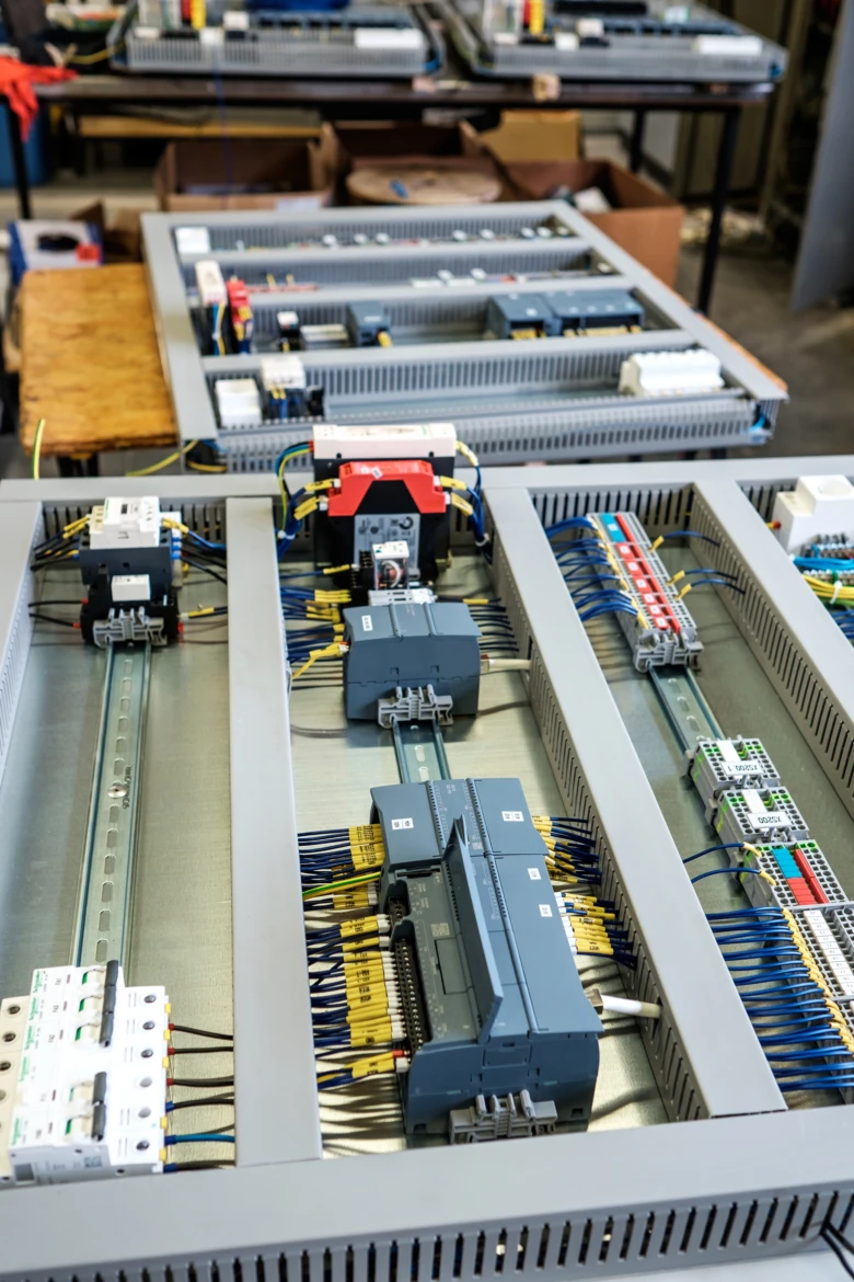Otevřený průmyslový elektrický panel s řádky komponentů a kabeláže.