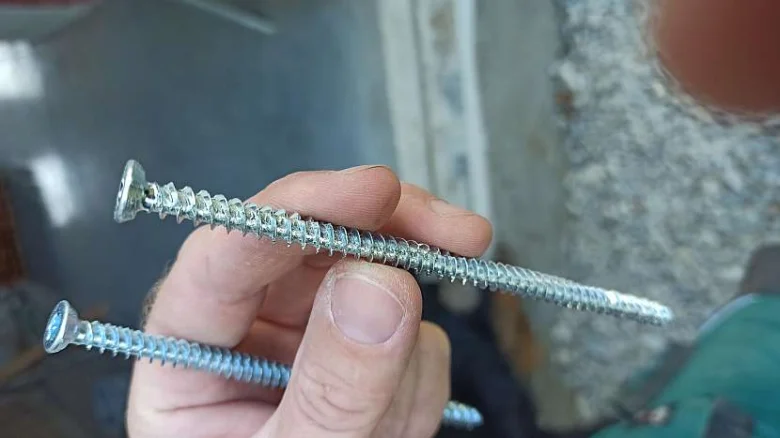 Ruce drží dva turbošrouby pro montáž do zdi.