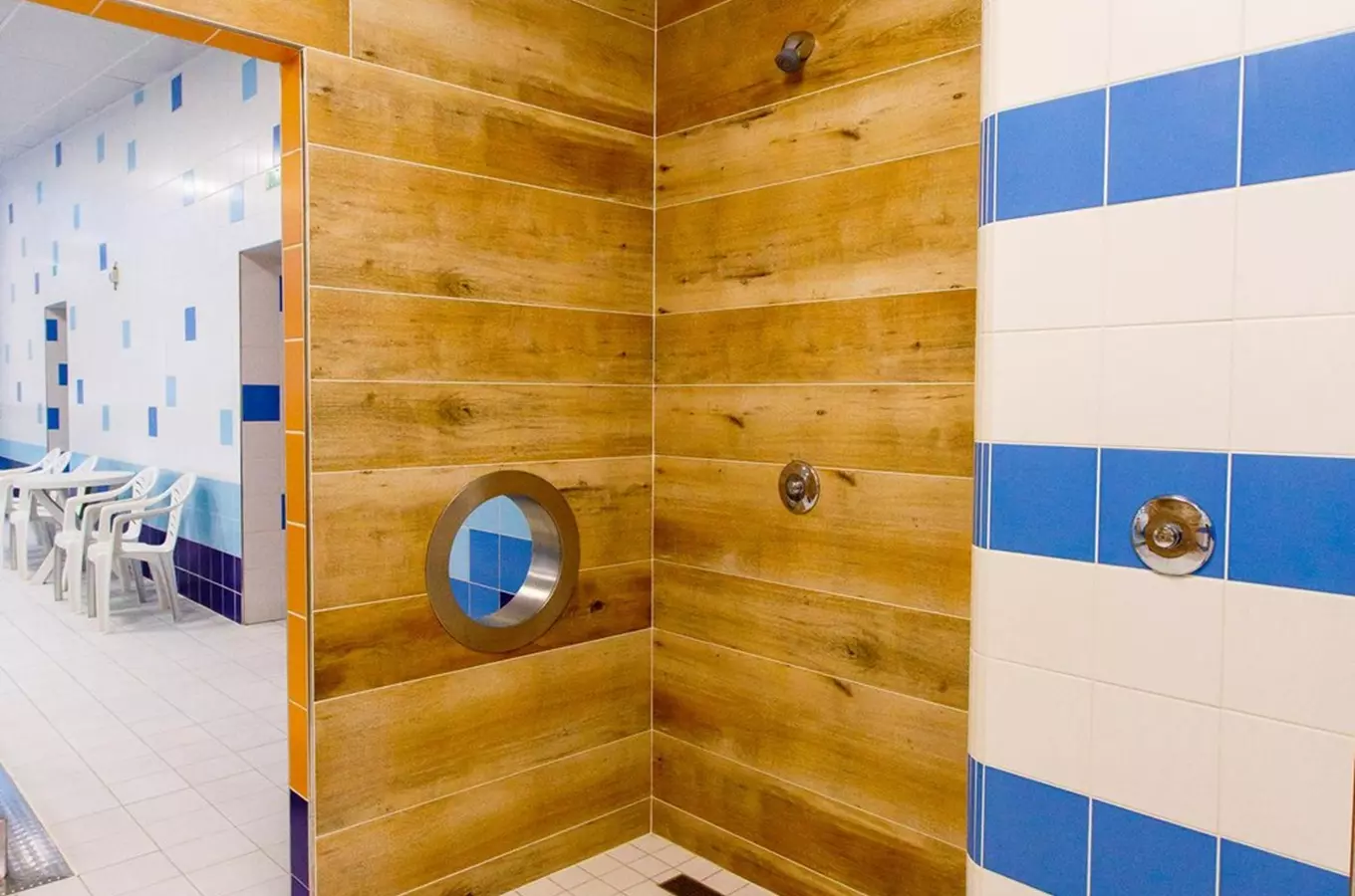 Moderní sprchový kout s dřevěnými panely a modro-bílou dlažbou.
