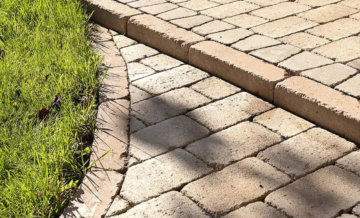 Betonový obrubník oddělující trávu od dlažby.