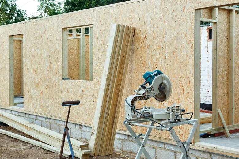 Stavba domu s dřevotřískovými deskami na exteriéru.