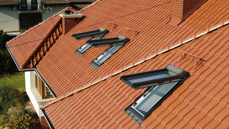 Červená sedlová střecha s valbovými okny.