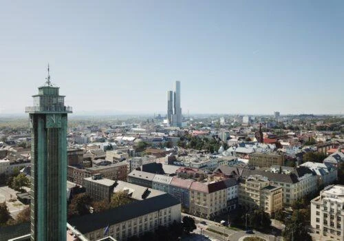 Pohled na ostravské město s historickou věží a mrakodrapy v pozadí.