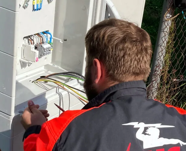 Elektrikář pracuje na zapojení elektroměrového rozvaděče s viditelnými vodiči.