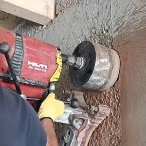Červený vrták jádrovým způsobem vrtá do betonu.