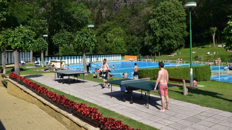 Venkovní koupaliště v Divoké Šárce s bazény, stoly na stolní tenis a lidé.