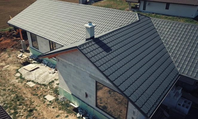 Montáž oplechování střechy s závětnými lištami na stavbě domu.