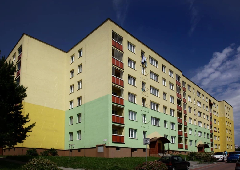 Barevná fasáda bytového domu po revitalizaci pod modrou oblohou.