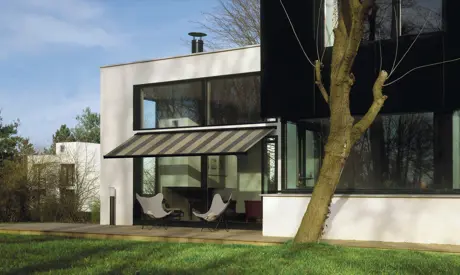 Moderní dům s venkovní žaluziovou markýzou na balkóně.