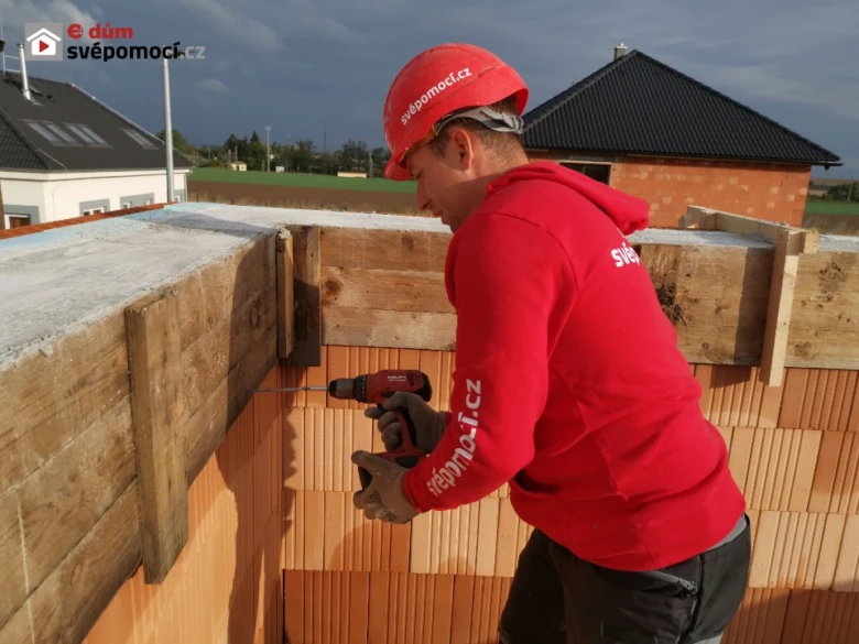 Stavebník armuje betonový věnc pomocí dřevěného bednění.