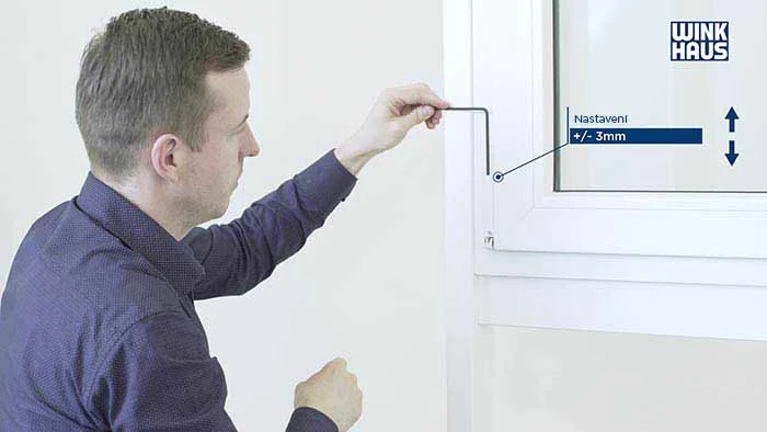 Muž nastavuje plastové okno pomocí nástroje pro úpravu.