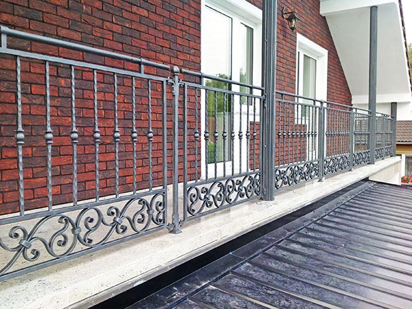 Kovové zábradlí s ozdobným designem na balkóně u domu.
