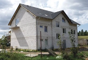 Dvoupatrový dům z porobetonu ve fázi stavby s viditelnými bloky a střechou.