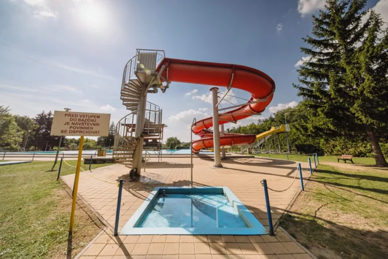Červená vodní skluzavka s bazénem v koupališti.