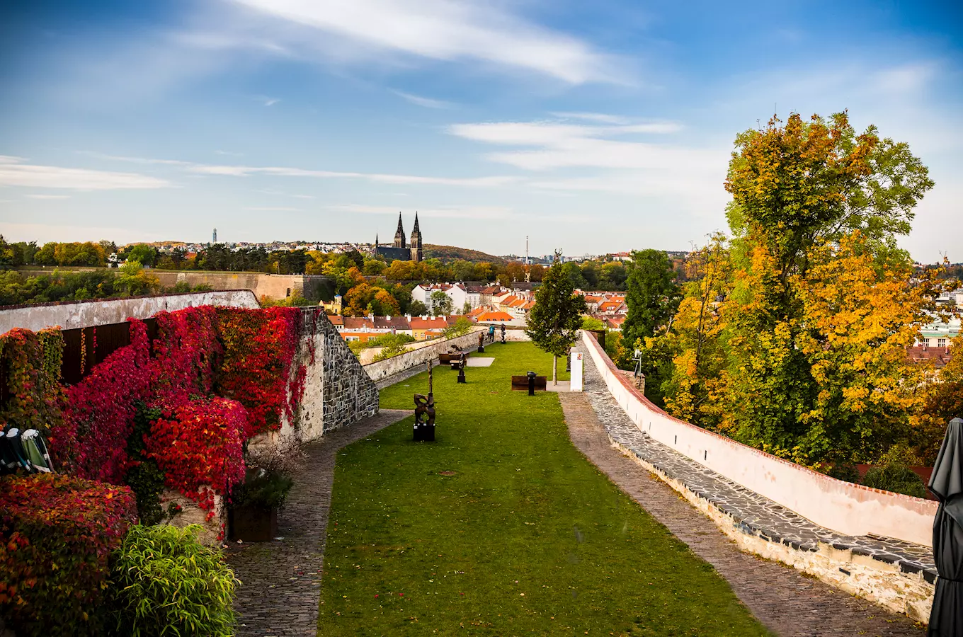 Zpevněná zahrada s výhledem na město a kostel.