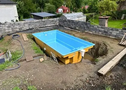 Zapuštěný bazén v žlutém obalu na stavbě zahradního pozemku.