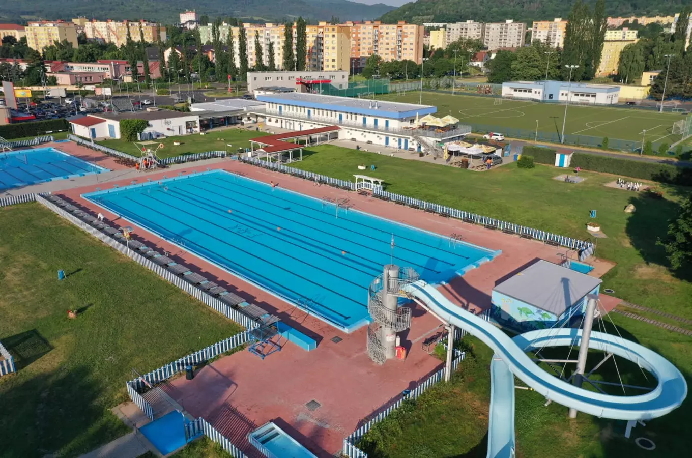 Vzdušný pohled na venkovní plavecký bazén s vodním skluzavkou v Kadaně.