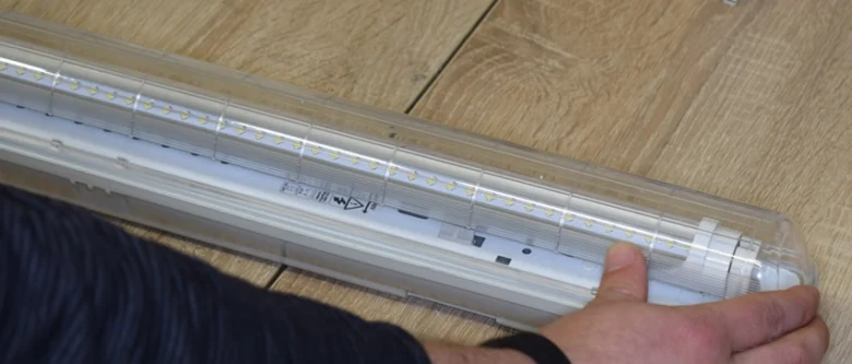 Nová LED zářivka v plastovém obalu na dřevěné podlaze.