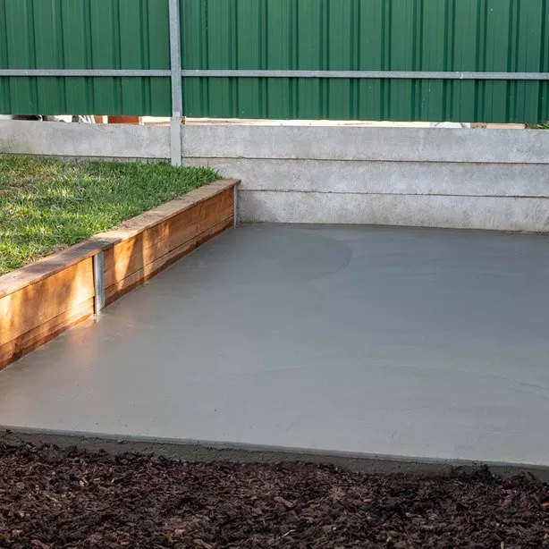 Čerstvě nalitá betonová podlaha vedle dřevěného zdi.