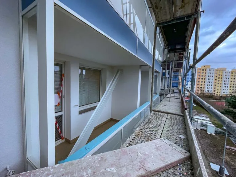 Přestavba lodžie s opěrným schodištěm a provizorním ohradním zábradlím.