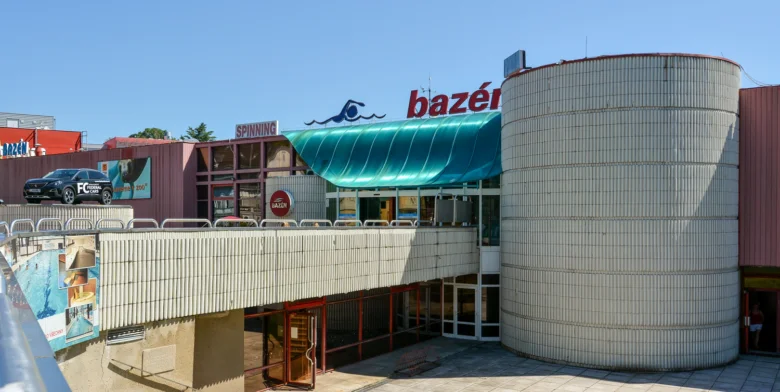 Exteriér plaveckého bazénu v Liberci s cylindrickou budovou.